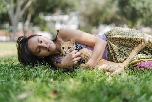 Femme allongée dans l'herbe avec son chat, communication animale