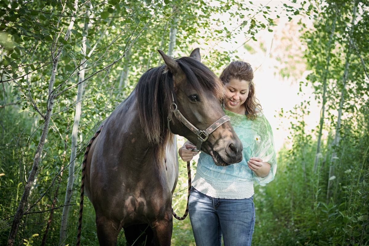 Hélène Vermette avec son cheval dans une forêt de bouleaux